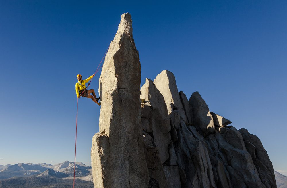 a man in yellow jacket is climbing the rocks